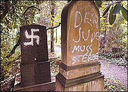    
June 27, 2004. Grave Desecration. A Jewish gravestone in Dusseldorf, Germany, is pictured on Friday, after more than 40 desecrated graves were discovered at the Jewish cemetery. Nazi and SS symbols were also sprayed in silver paint nearby. Police said they did not know yet who was responsible for the vandalism. Photo: AP.